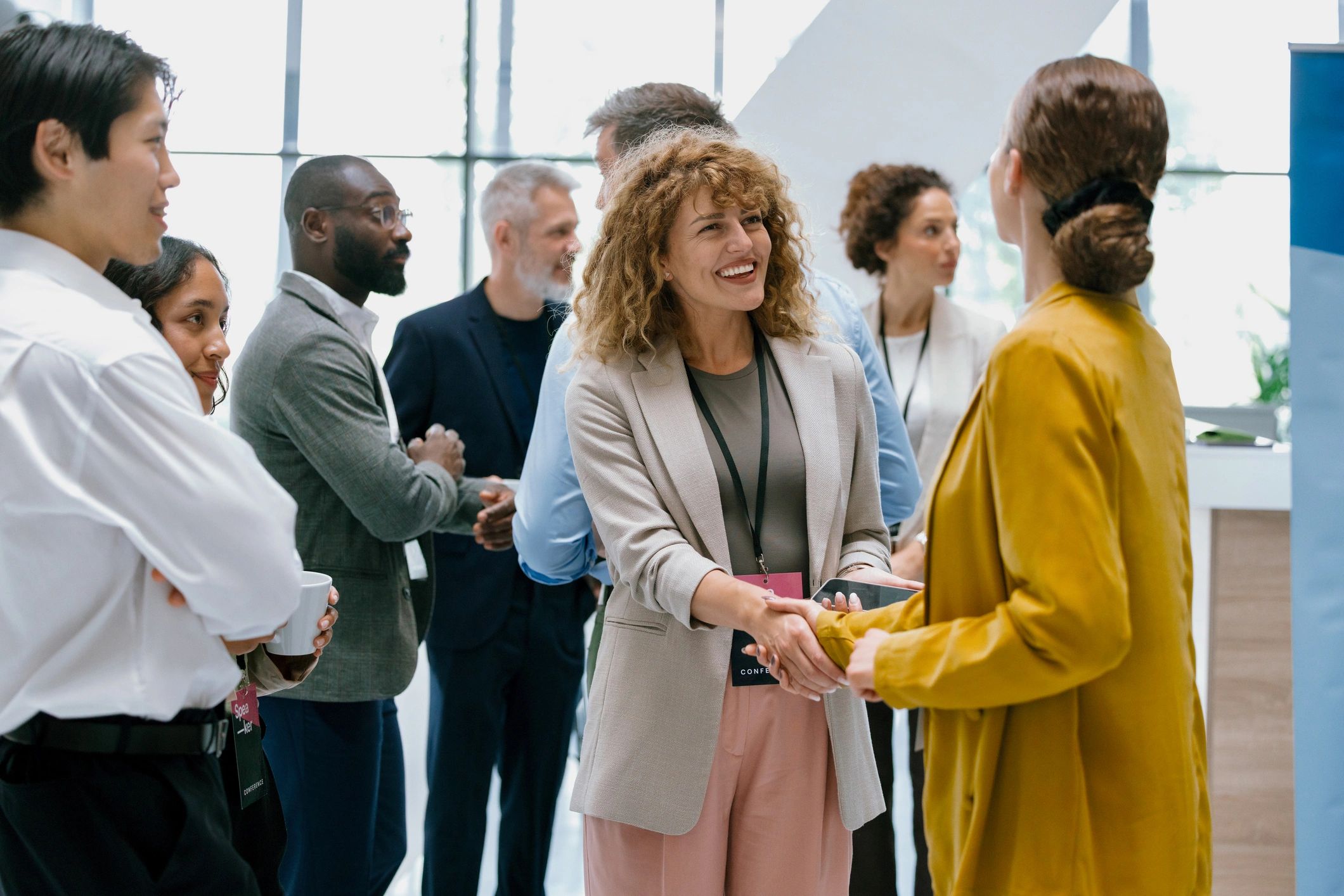 Confident businesswomen handshaking while in the corridor in front of the conference hall